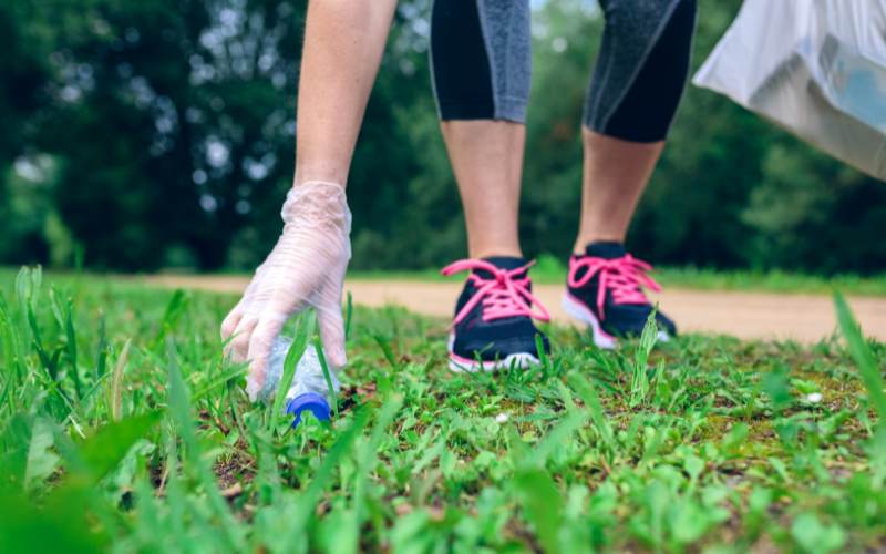 Plogging - eine Frau hebt beim Joggen Müll auf.